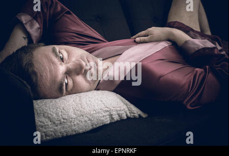 Mann liegen und ruht auf dem Sofa zu Hause. Er ist in Gedanken mit einem nachdenklichen und deprimiert Blick verloren. Stockfoto