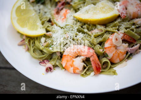 Schüssel mit Spinat Tagliatelle Pasta mit König Garnelen, Meeresfrüchte, Oregano, Rosmarin und geriebenem Grana Padano Käse. Stockfoto