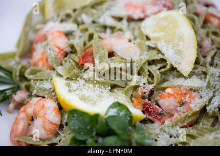 Schüssel mit Spinat Tagliatelle Pasta mit König Garnelen, Meeresfrüchte, Oregano, Rosmarin und geriebenem Grana Padano Käse. Stockfoto