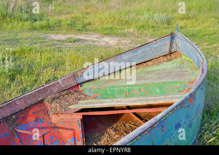 Bunte verlassenen Ruderboot auf der Wiese am Ufer eines kleinen Sees Stockfoto