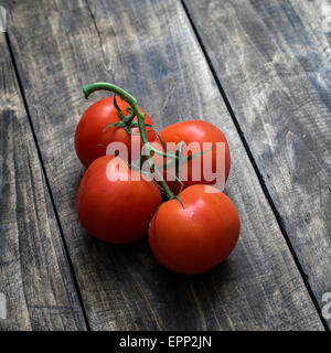 Frisch gepflückt Reife rote Tomaten aus der Rebe auf einem alten rustikalen Garten Holztisch liegend Stockfoto