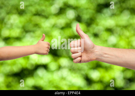 Vater und Sohn Hände geben wie auf natürlichen grünen Hintergrund Stockfoto