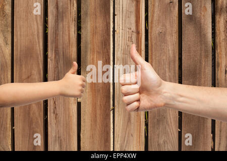 Vater und Sohn Hände geben wie auf Holzwand Hintergrund. Stockfoto