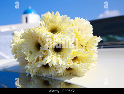 Bouquet von gelben Chrysanthemen auf der Motorhaube des Autos. Im Hintergrund der griechischen Kirche. Stockfoto