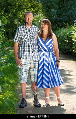 Hübscher behinderten Mann trägt einen künstliches Bein stehend Arm in Arm mit einer attraktiven Frau im Freien in der Landschaft lächelnd Stockfoto
