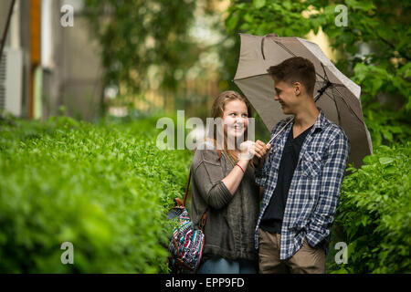 Junges Paar Mann und ein Mädchen im Freien unter einem Dach im kleinen Regen. Stockfoto