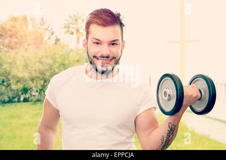ein lächelnder junger Mann während seiner Fitness-Übungen im freien warm Filter angewendet Stockfoto