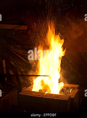 Feuer mit fliegenden Funken Closeup auf dunklen Schmied Arbeitsplatz Hintergrund Stockfoto