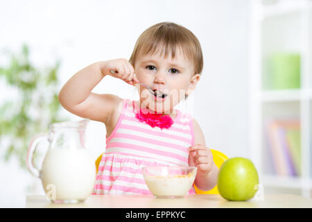 glückliches Kind niedlich Mädchen Essen selbst mit Löffel Stockfoto