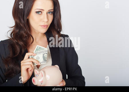 junge Frau mit einem Dollar und Sparschwein in der hand Stockfoto