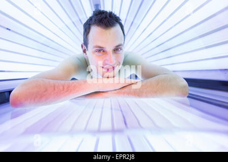 Hübscher junger Mann während einer Bräunungssitzung in ein modernes Solarium entspannen, kümmert sich um sich selbst, genießen die künstliche sunli Stockfoto
