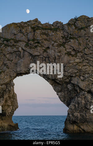 Nahaufnahme von Durdle Door in den Abend mit den aufgehenden Mond darüber, Dorset, England. Durdle Door ist eines der vielen beeindruckenden l Stockfoto