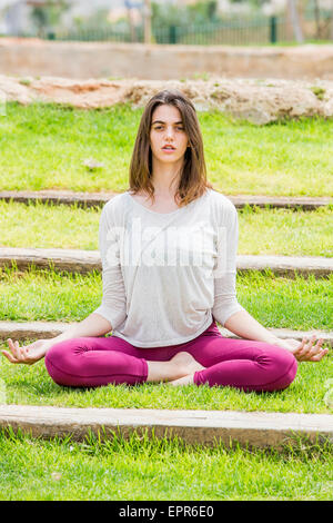 Junge Frau MakinYoung Frau machen ihre Yoga-Übungen im Park am Stairsg Yoga im Park Model release verfügbar Stockfoto