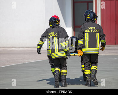 Vier tapfere Feuerwehrmänner tragen anderen Feuerwehrmann mit medizinischen Bahre Stockfoto