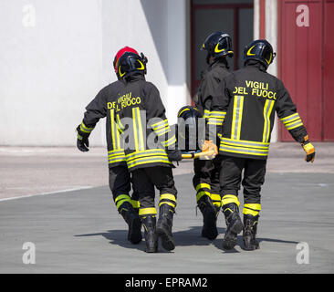 Vier tapfere Feuerwehrmänner tragen einen anderen Feuerwehrmann mit der Bahre Stockfoto