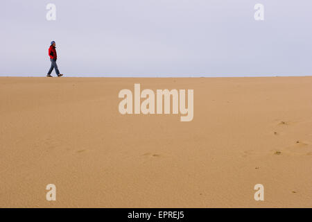 Eine junge Frau in ihren frühen dreißiger Jahren wandelt unter den Sanddünen, Florence, Oregon, Vereinigte Staaten. Stockfoto