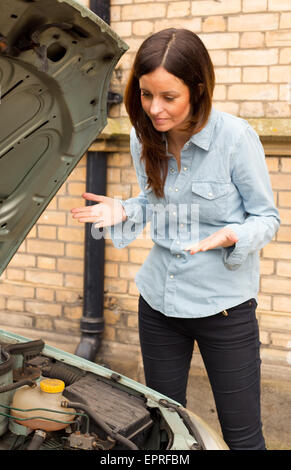 junge Frau, die verärgert über den Motor ihres Autos Stockfoto