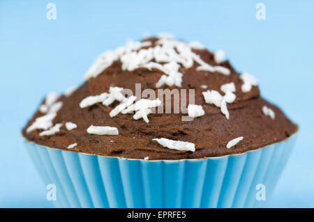 Schokolade und Kokos Kuchen oder Fee-Kuchen mit Zuckerguss und Kokosnuss Schokostreuseln auf blauem Hintergrund Stockfoto