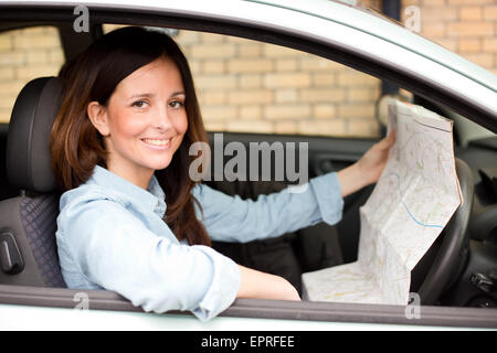 junge Frau, die im Besitz einer Karte in einem Auto sitzen Stockfoto