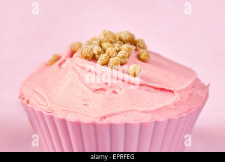 Ziemlich bunt dekorierten Kuchen oder Fee Kuchen mit rosa Zuckerguss und winzige Fudge Stücke auf einem rosa Hintergrund Stockfoto