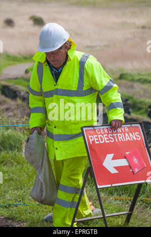 Arbeiter mit Fußgänger-Umlenkschild - Arbeiter legen neuen Weg in Porthgain, Pembrokeshire Coast National Park, Wales, Großbritannien im Mai Stockfoto