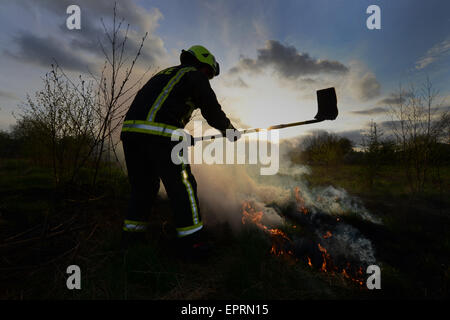 Ein Feuerwehrmann Außerbetriebnahme Flammen an einem Feld Feuer. Bild: Scott Bairstow/Alamy Stockfoto