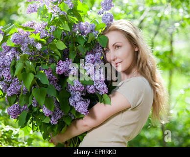 glückliche junge Frau im Park mit einem großen Blumenstrauß ein lila Stockfoto