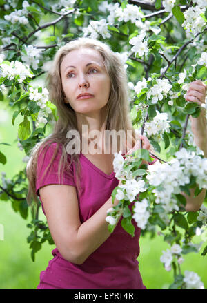 Junge attraktive Frau stehen in der Nähe des blühenden Apfelbaums Stockfoto