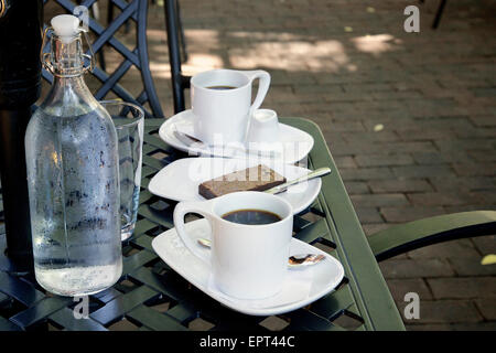 Kaffee, Brownie und Flasche Wasser bei Terrassentisch im Cafe, Dundas, Ontario, Kanada Stockfoto