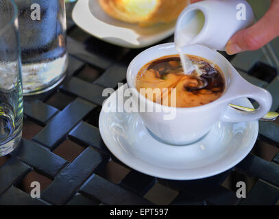 Creme, gegossen in Kaffee in weißen Tasse und Untertasse auf outdoor, Terrassentisch, Kanada Stockfoto