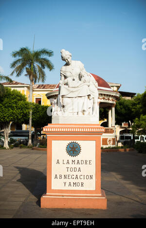 Mutterschaft Statue Parque Central Granada Nicaragua // GRANADA, Nicaragua — Eine Statue zu Ehren der Mutterschaft steht an prominenter Stelle im Parque Central, dem Hauptplatz und dem historischen Herzen von Granada. Auf dem Denkmal steht eine Inschrift mit der Aufschrift „Mutter aller Hingabe und Liebe“, die die Hingabe der Mutter feiert. Der Parque Central ist ein zentraler Treffpunkt für Einheimische und Besucher in Granada, einer der ältesten Kolonialstädte Nicaraguas. Der Platz ist von farbenfroher spanischer Kolonialarchitektur und wichtigen Bürgerhäusern umgeben. Dieses öffentliche Kunstwerk stellt eines von vielen Kulturdenkmälern dar Stockfoto
