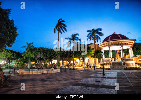 GRANADA, Nicaragua – Ein Brunnen und eine Pergola stehen in der Mitte des Parque Central in der Abenddämmerung. Der Parque Central ist der Hauptplatz und das historische Herz von Granada, Nicaragua. Stockfoto