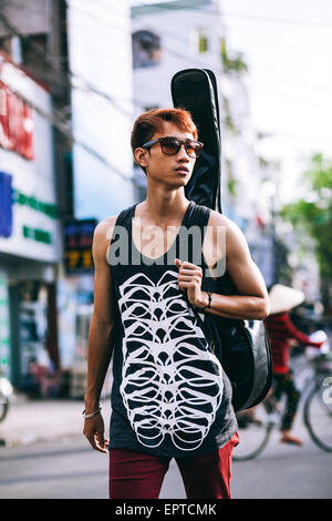 asiatischen Gitarristen Künstler Mann mit Sonnenbrille auf Vietnamesisch Straße gehen Stockfoto