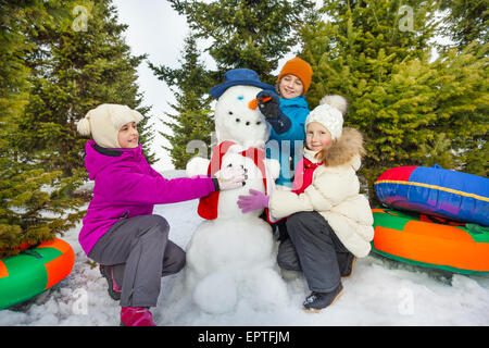 Lächelnde Kinder machen niedlichen Schneemann im Wald Stockfoto