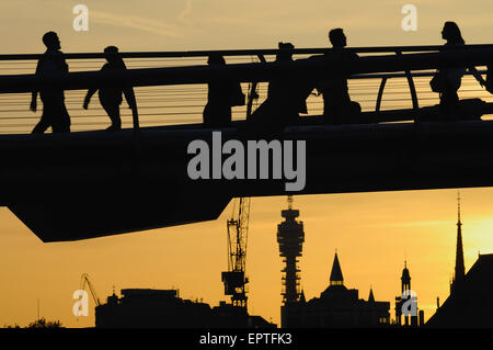 Fußgänger in Silhouette auf der Millennium Bridge, London UK, in der Dämmerung, mit Gebäude im Hintergrund Stockfoto