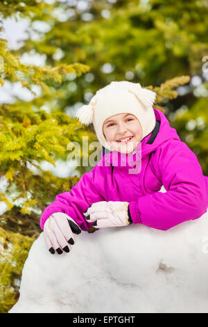 Nahaufnahme des glücklichen Mädchen steht hinter der Schneewand Stockfoto