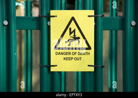 Gefahr von Tod, heraus halten! Gelbe Warnblinkleuchten Zeichen für die Sicherheit Zaun ein Strom sub Station verbunden. England, Vereinigtes Königreich. Stockfoto