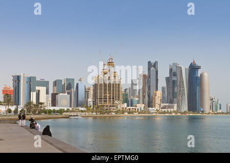 Junge Katarer sitzen am Wasser mit Doha Wolkenkratzer im Blick Stockfoto