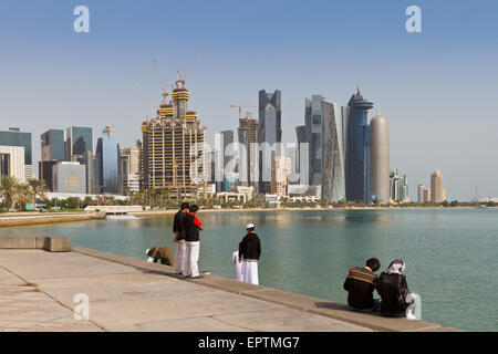 Junge Katarer sitzen am Wasser mit Doha Wolkenkratzer im Blick Stockfoto