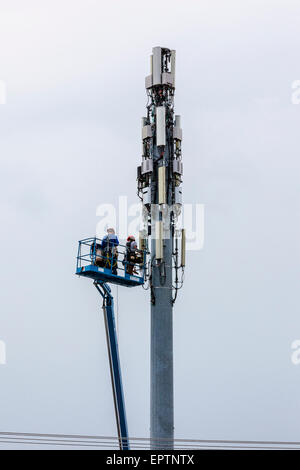 Zwei Männer arbeiten aus einem Aufzug Eimer auf einem Handy oder Handy Turm in Modesto, Kalifornien Stockfoto