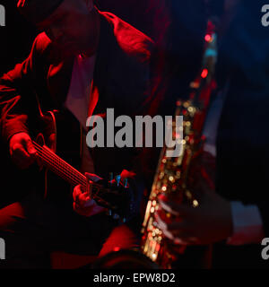 Gitarrist, reifer Mann, Saxophonist im Vordergrund und rauchigen Bühne auf Hintergrund Stockfoto