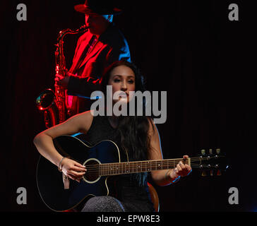 Schöne Frau spielt eine Gitarre, verrauchten Bühne auf Hintergrund Stockfoto