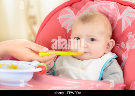 Baby Boy in einen Hochstuhl zu Hause essen Stockfoto