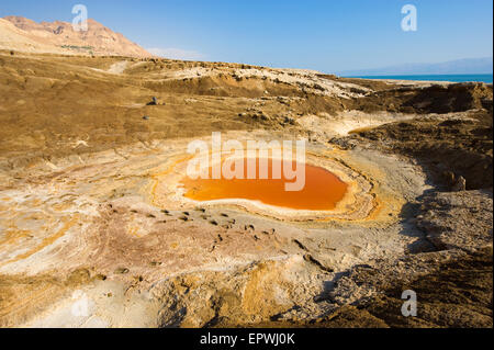 Doline oder Tagebau mit orange Salzwasser am Ufer des Toten Meeres am Ende des Sommers der Wasserstand im wird Stockfoto