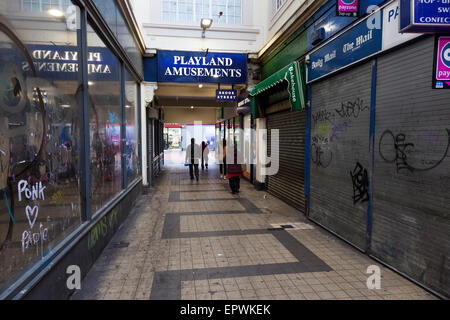 Vandalized Geschäften in einem heruntergekommen, schmutzig Stadtzentrum Arcade. Shop Fronten mit Graffiti auf Fenstern und Fensterläden. Der Park Street Arcade, Walsall, England, Großbritannien Stockfoto