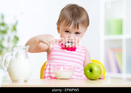 glückliches Kind Mädchen gesunde Lebensmittel selbst mit Löffel Stockfoto