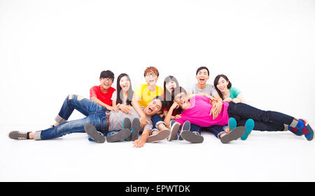 Glückliche junge Gruppe zusammensitzen gegen weiße Wand Stockfoto