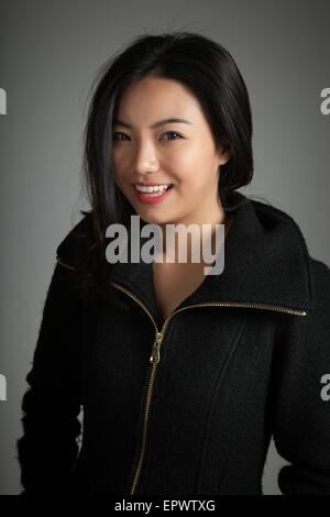 Attraktive asiatische Mädchen in ihren Zwanzigern isoliert auf Plein Hintergrund in einem Studio gedreht Stockfoto