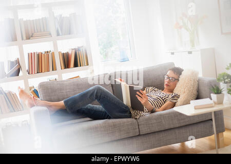Ältere Frau liest Buch auf sofa Stockfoto
