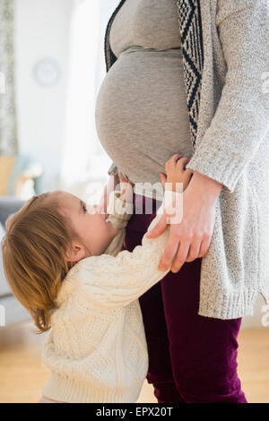 Mädchen (2-3) erreichen nach schwangere Mutter Stockfoto